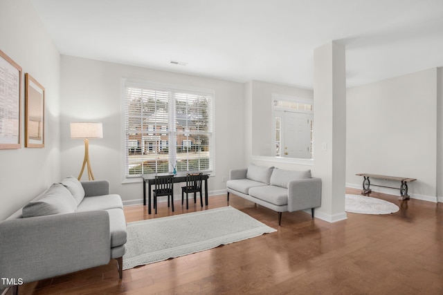 living room featuring visible vents, baseboards, and wood finished floors