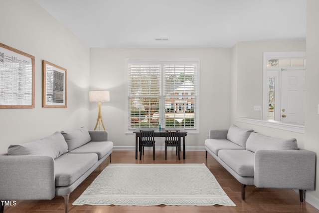 living area featuring visible vents, wood finished floors, and baseboards