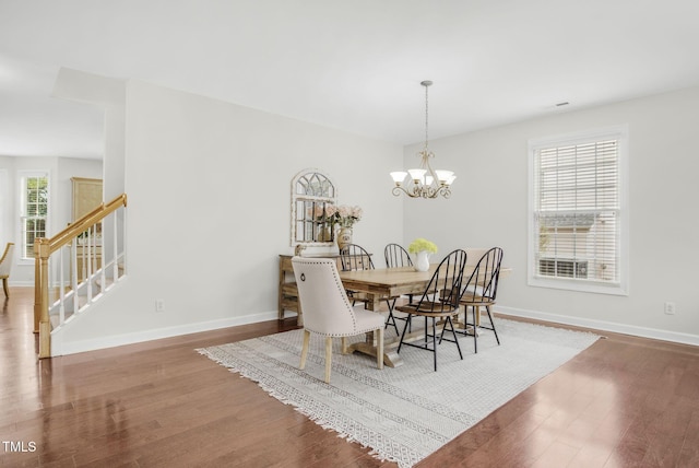 dining area with stairs, a notable chandelier, wood finished floors, and baseboards