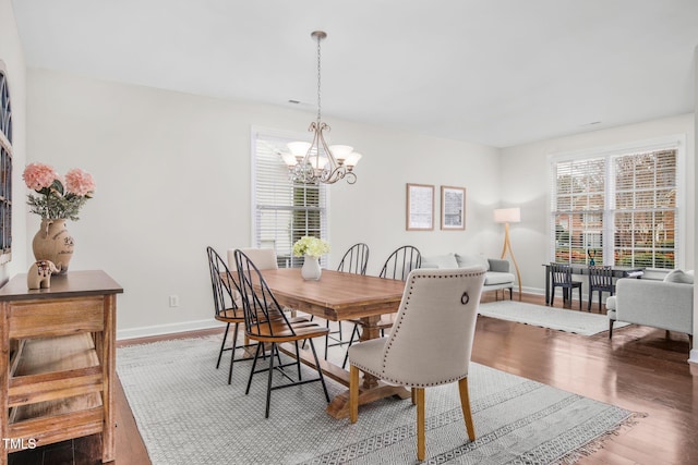 dining room featuring an inviting chandelier, wood finished floors, baseboards, and a wealth of natural light