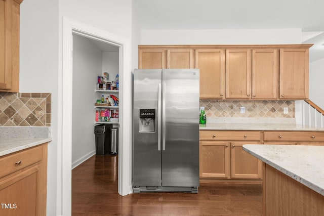 kitchen with light stone counters, decorative backsplash, stainless steel fridge, and dark wood-style flooring