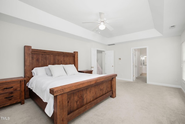 bedroom featuring visible vents, light colored carpet, a raised ceiling, and baseboards