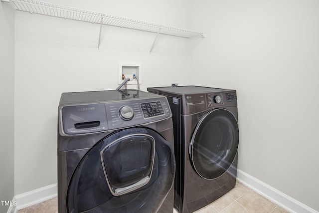 laundry room with tile patterned floors, baseboards, washing machine and dryer, and laundry area