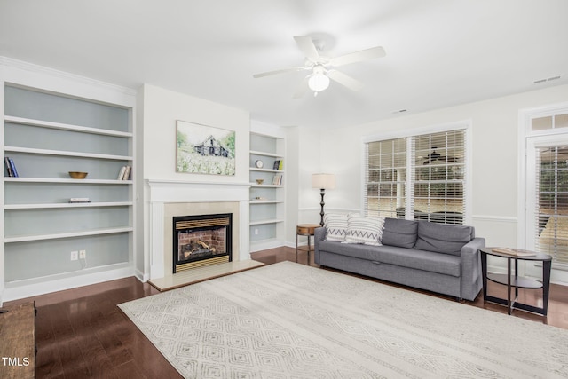 living area with a glass covered fireplace, wood finished floors, baseboards, and a ceiling fan