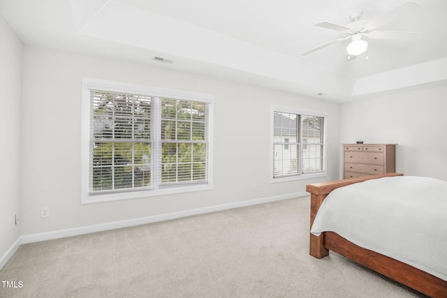 bedroom featuring visible vents, a raised ceiling, baseboards, light colored carpet, and ceiling fan