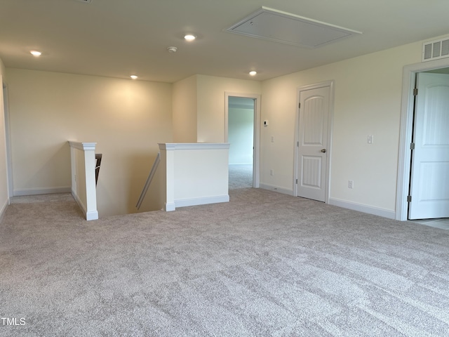 carpeted spare room featuring baseboards, visible vents, attic access, and recessed lighting