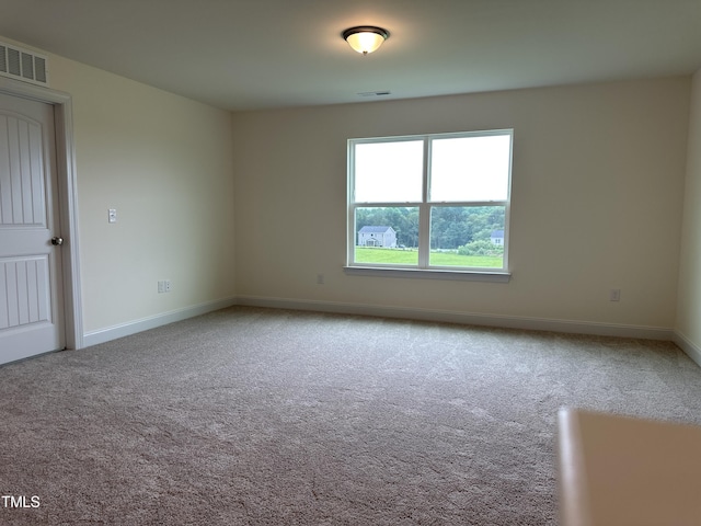 carpeted spare room featuring visible vents and baseboards