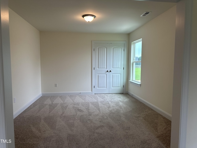 carpeted spare room with visible vents and baseboards