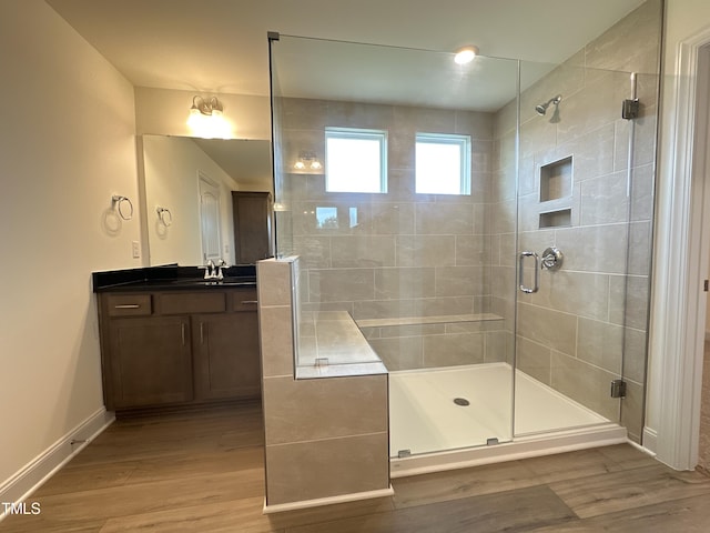 full bath featuring a shower stall, baseboards, wood finished floors, and vanity