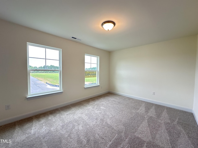 carpeted empty room featuring baseboards and visible vents