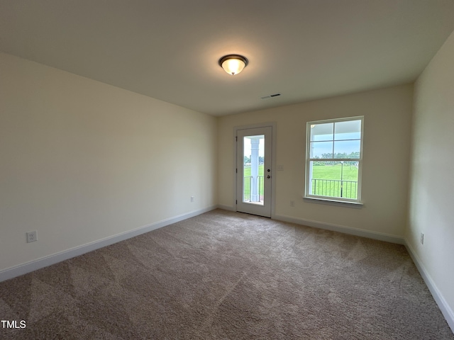 carpeted spare room featuring baseboards and visible vents