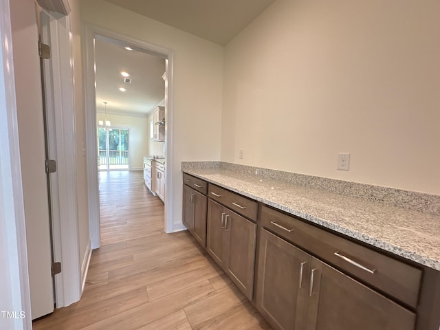 corridor featuring baseboards, an inviting chandelier, and light wood-style floors