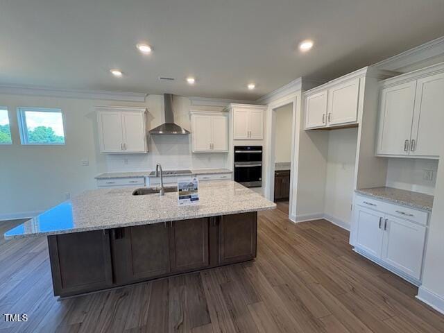123 Sage Ln Unit 010, Four Oaks, NC 27524 - kitchen with wall chimney range hood, a sink, double oven, a kitchen island with sink, and dark wood-type flooring