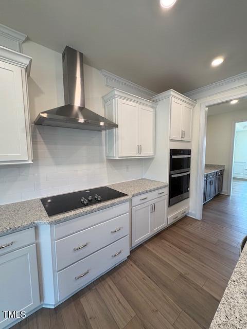 123 Sage Ln Unit 010, Four Oaks, NC 27524 - kitchen with wall chimney exhaust hood, black electric stovetop, double oven, white cabinetry, and dark wood-type flooring