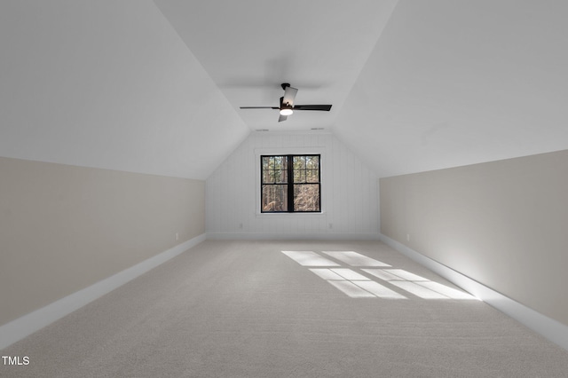 additional living space featuring light carpet, lofted ceiling, a ceiling fan, and baseboards