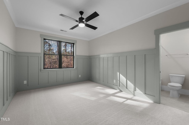 empty room with light carpet, ornamental molding, a wainscoted wall, and visible vents