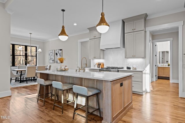 kitchen with a kitchen breakfast bar, custom exhaust hood, a large island with sink, and pendant lighting