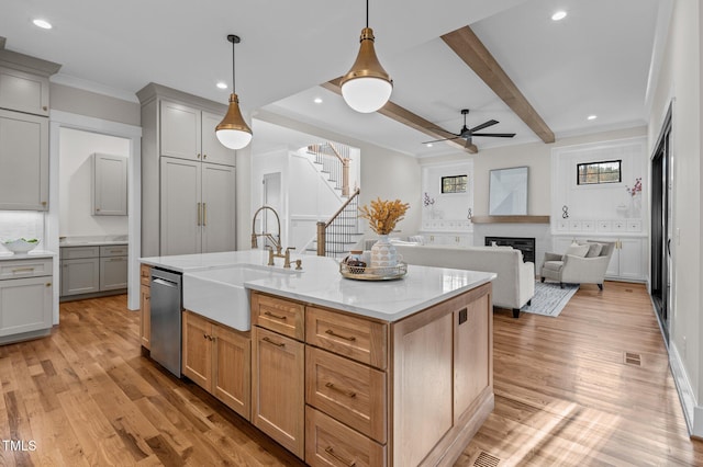 kitchen featuring decorative light fixtures, a center island with sink, open floor plan, a sink, and dishwasher