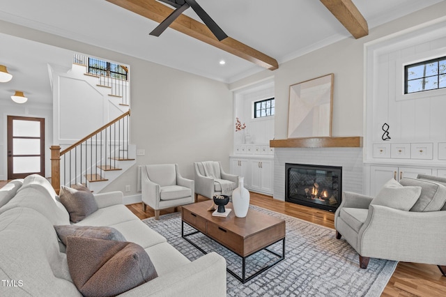 living room with recessed lighting, light wood-style flooring, a brick fireplace, beamed ceiling, and stairs