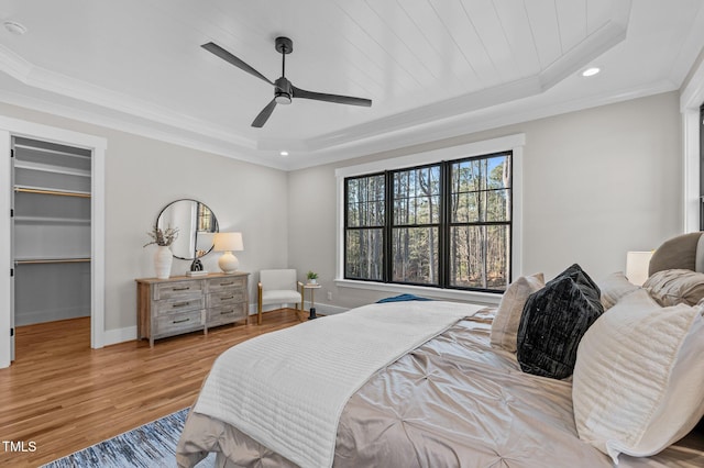 bedroom with ornamental molding, a raised ceiling, baseboards, and wood finished floors