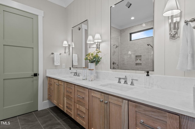 bathroom featuring double vanity, tiled shower, tile patterned flooring, and a sink