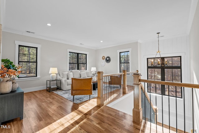 living room with crown molding, a notable chandelier, visible vents, light wood-style flooring, and baseboards