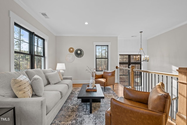 living area featuring visible vents, wood finished floors, a wealth of natural light, and an inviting chandelier