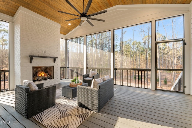 sunroom / solarium featuring vaulted ceiling, ceiling fan, an outdoor brick fireplace, and wood ceiling