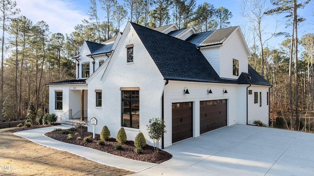 view of property exterior featuring a garage, concrete driveway, brick siding, and roof with shingles