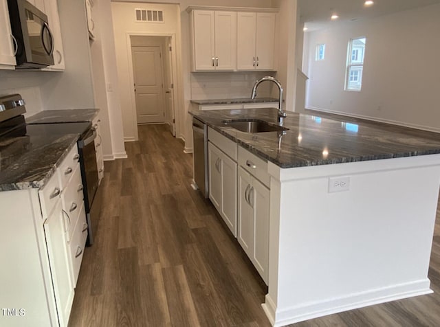 kitchen with white cabinets, black appliances, a kitchen island with sink, dark hardwood / wood-style floors, and sink