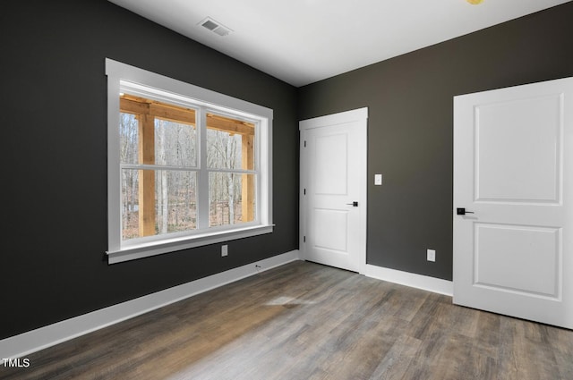 spare room with a wealth of natural light and dark hardwood / wood-style floors