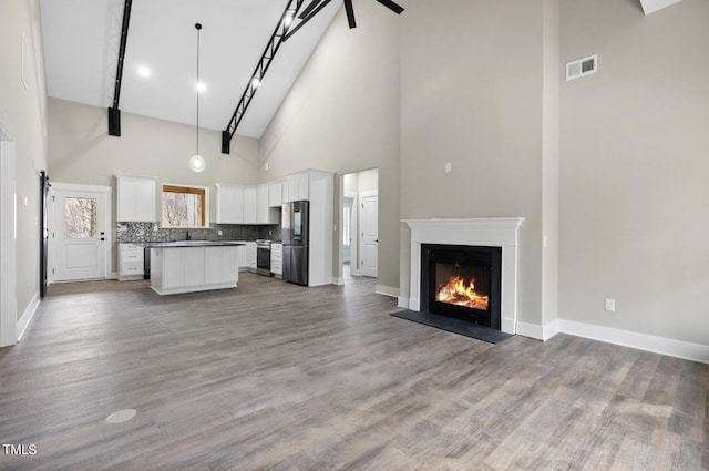 unfurnished living room with high vaulted ceiling, wood-type flooring, and beamed ceiling