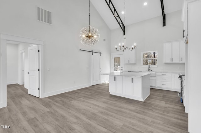 kitchen featuring hanging light fixtures, a center island, high vaulted ceiling, wood-type flooring, and white cabinets