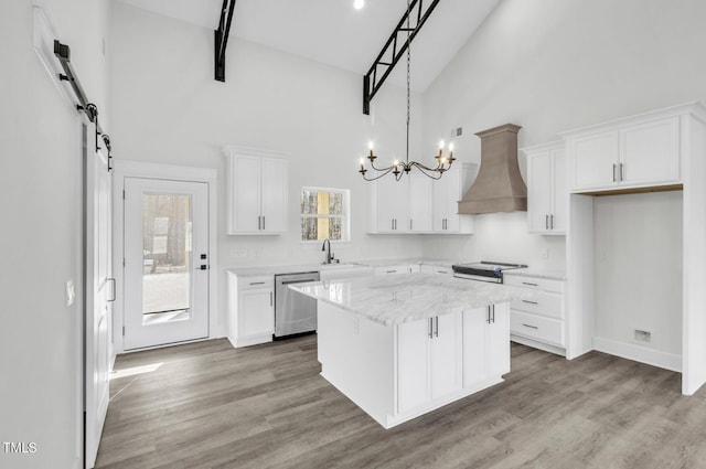 kitchen with a kitchen island, hardwood / wood-style floors, a towering ceiling, dishwasher, and custom exhaust hood