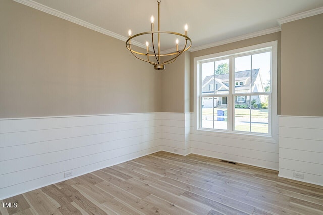 unfurnished room featuring a wainscoted wall, light wood-style flooring, visible vents, and crown molding