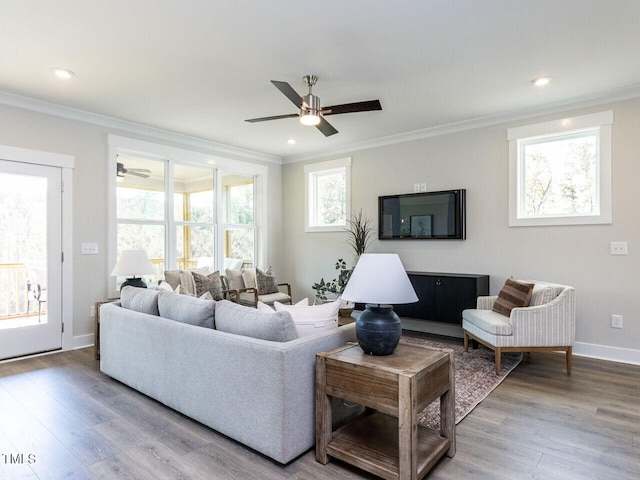 living area featuring baseboards, ornamental molding, ceiling fan, and wood finished floors