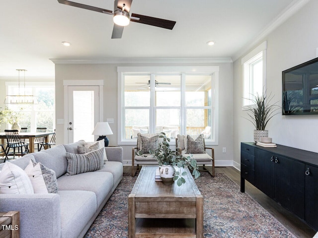 living area with baseboards, ornamental molding, a healthy amount of sunlight, and ceiling fan with notable chandelier