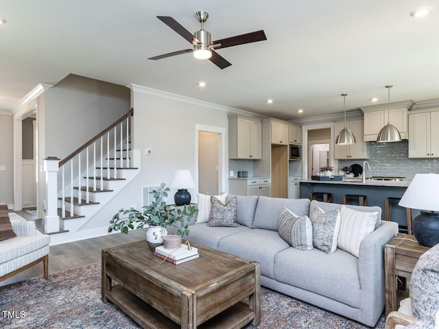 living area featuring wood finished floors, ornamental molding, recessed lighting, stairway, and a ceiling fan