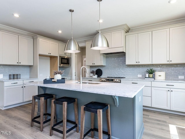 kitchen featuring backsplash, light wood-style floors, stainless steel appliances, and a sink