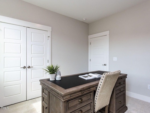 office area featuring baseboards and light carpet