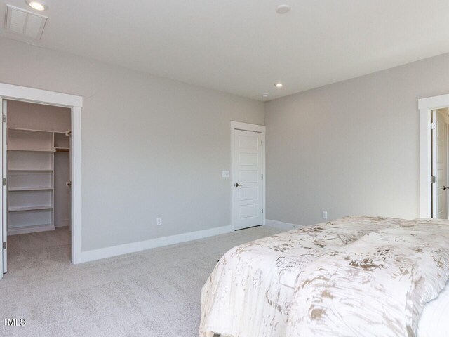 bedroom featuring recessed lighting, baseboards, visible vents, a walk in closet, and light carpet