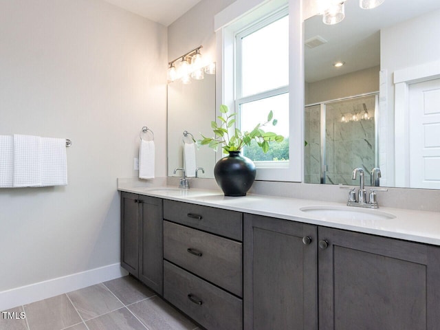 bathroom with a sink, double vanity, a stall shower, and baseboards