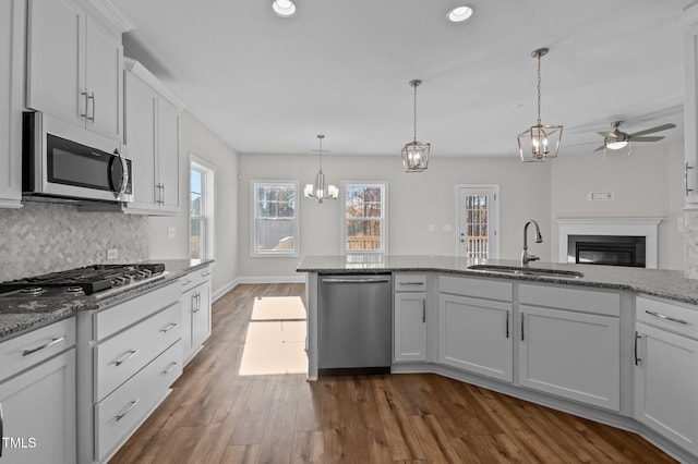 kitchen featuring stainless steel appliances, sink, dark hardwood / wood-style floors, white cabinetry, and hanging light fixtures