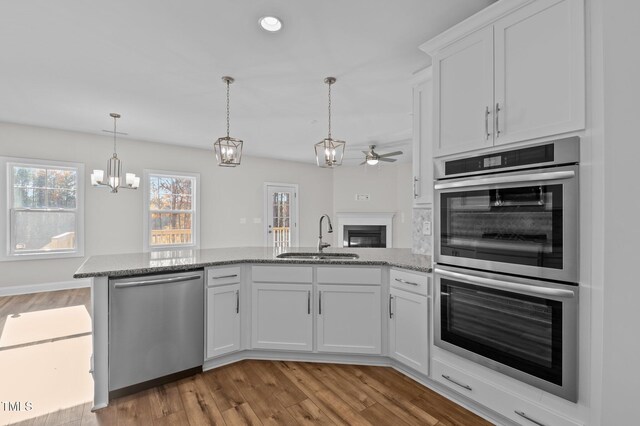 345 Sutherland Dr, Franklinton, NC 27525 - kitchen with appliances with stainless steel finishes, a sink, a ceiling fan, a peninsula, and a glass covered fireplace