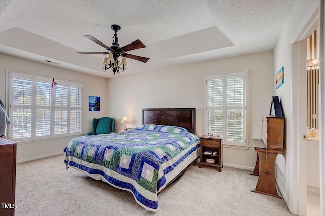 bedroom featuring ceiling fan, ensuite bathroom, light colored carpet, and multiple windows