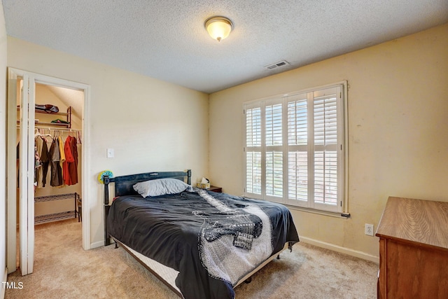 carpeted bedroom with a textured ceiling, a closet, and a walk in closet