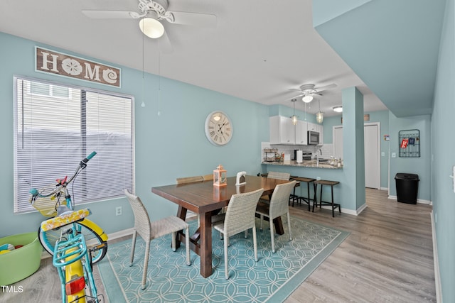 dining space with ceiling fan, sink, and light hardwood / wood-style flooring