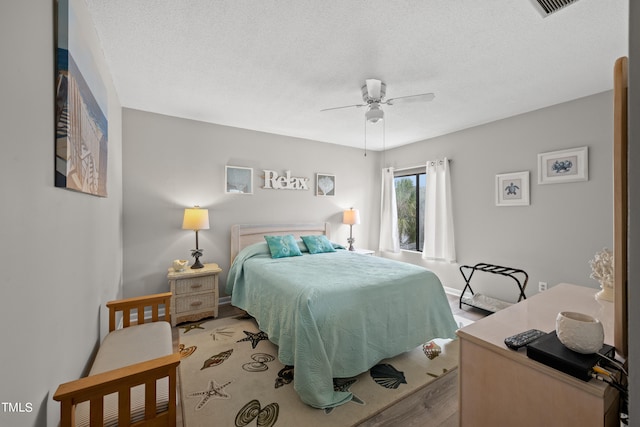 bedroom featuring ceiling fan, light hardwood / wood-style floors, and a textured ceiling