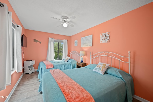 bedroom featuring ceiling fan, a textured ceiling, and light hardwood / wood-style flooring