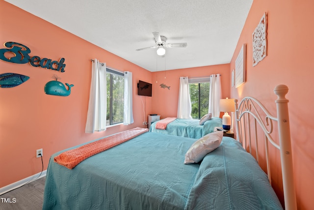 bedroom featuring a textured ceiling, hardwood / wood-style floors, multiple windows, and ceiling fan